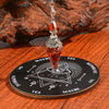 A crystal pendulum set featuring a red gemstone and silver findings displayed on a wooden divination board.
