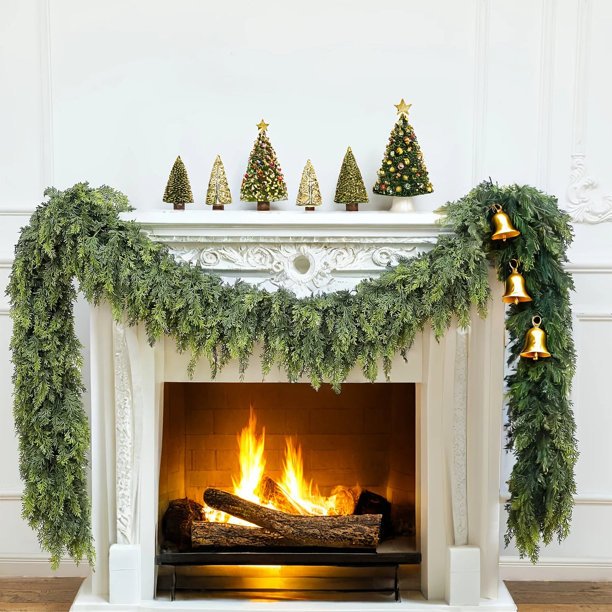 Extra long pine vine wreath draped over a white fireplace mantel with a lit fire.