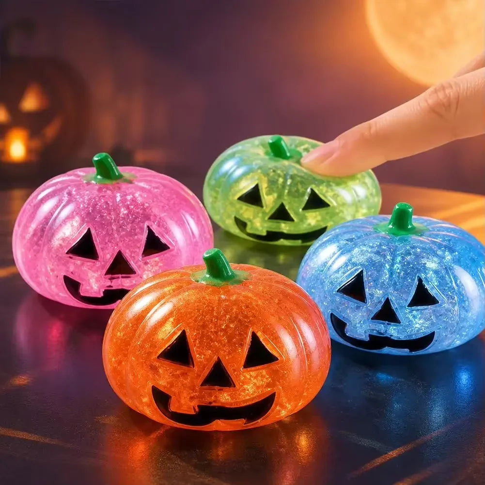 Hand holding a glittery orange Halloween pumpkin stress ball against a dark background.
