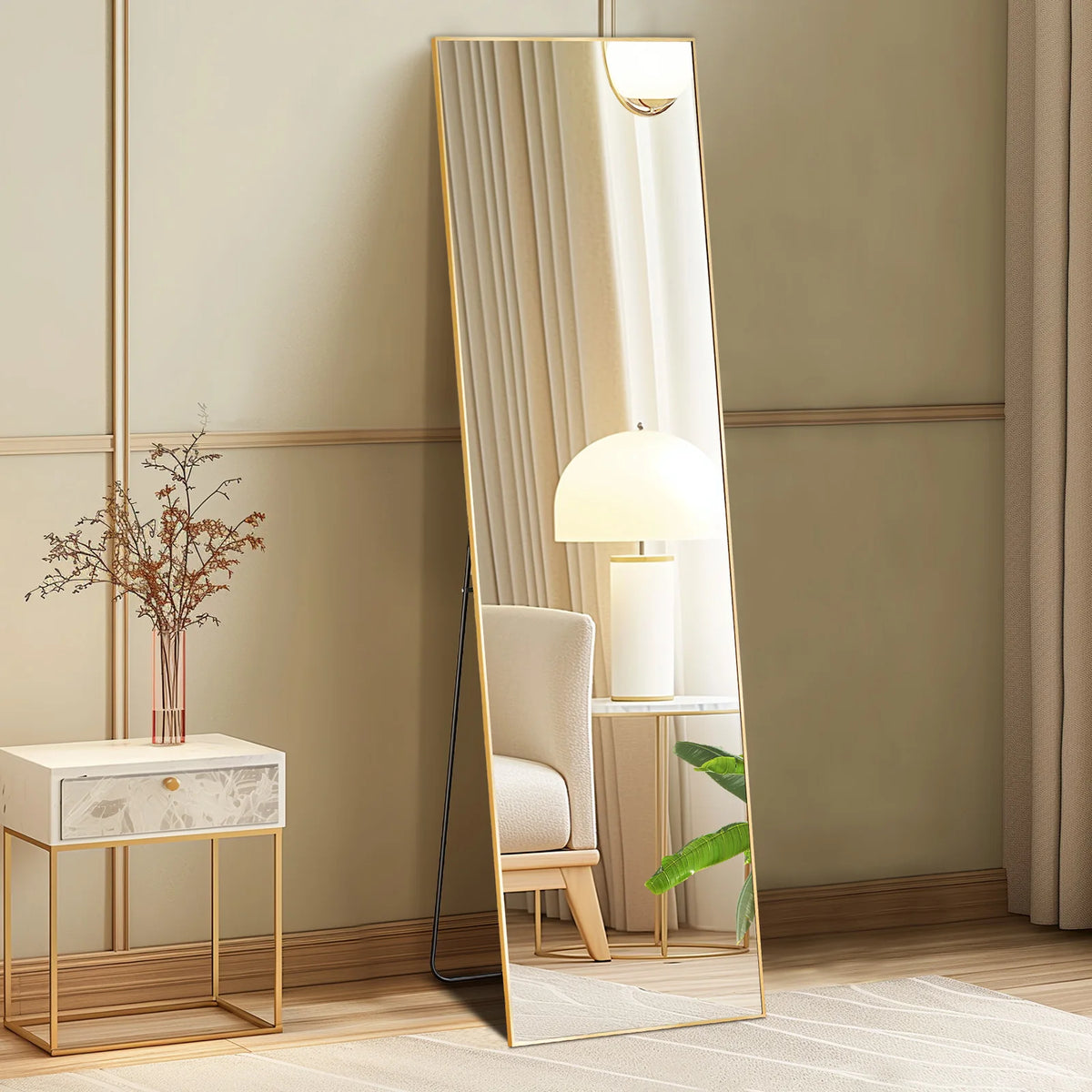 A full length arched wall mirror with a gold frame reflects a modern lamp and a chair in a light-colored room.