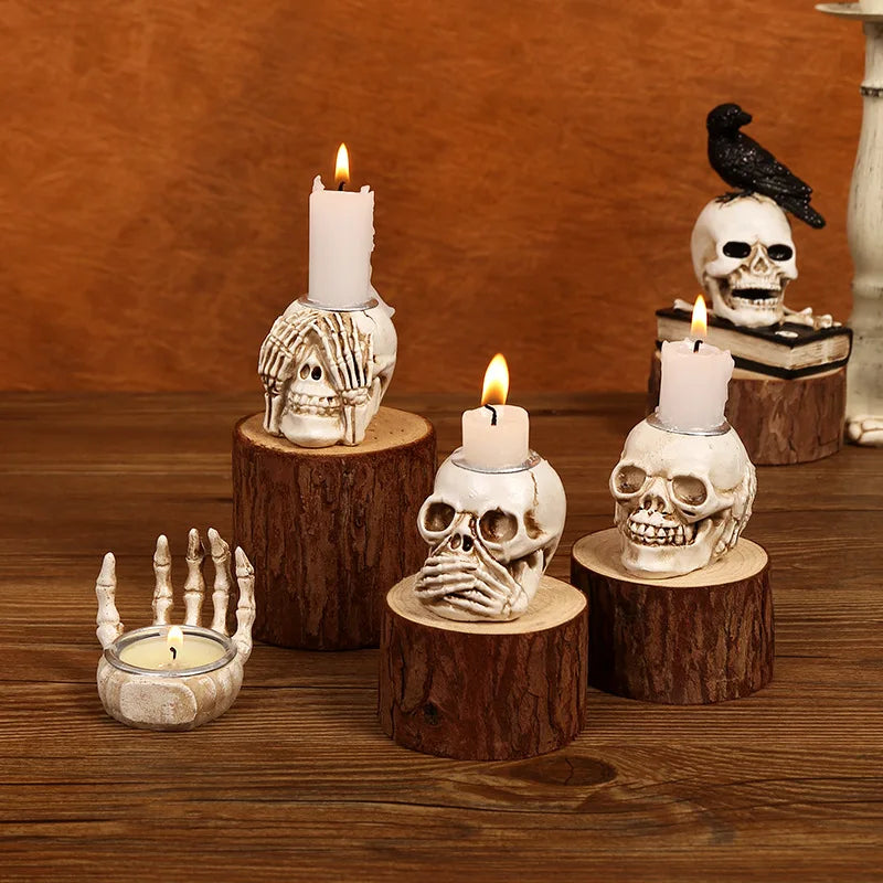 A collection of resin skull candle holders and a crow figurine displayed on a wooden surface.