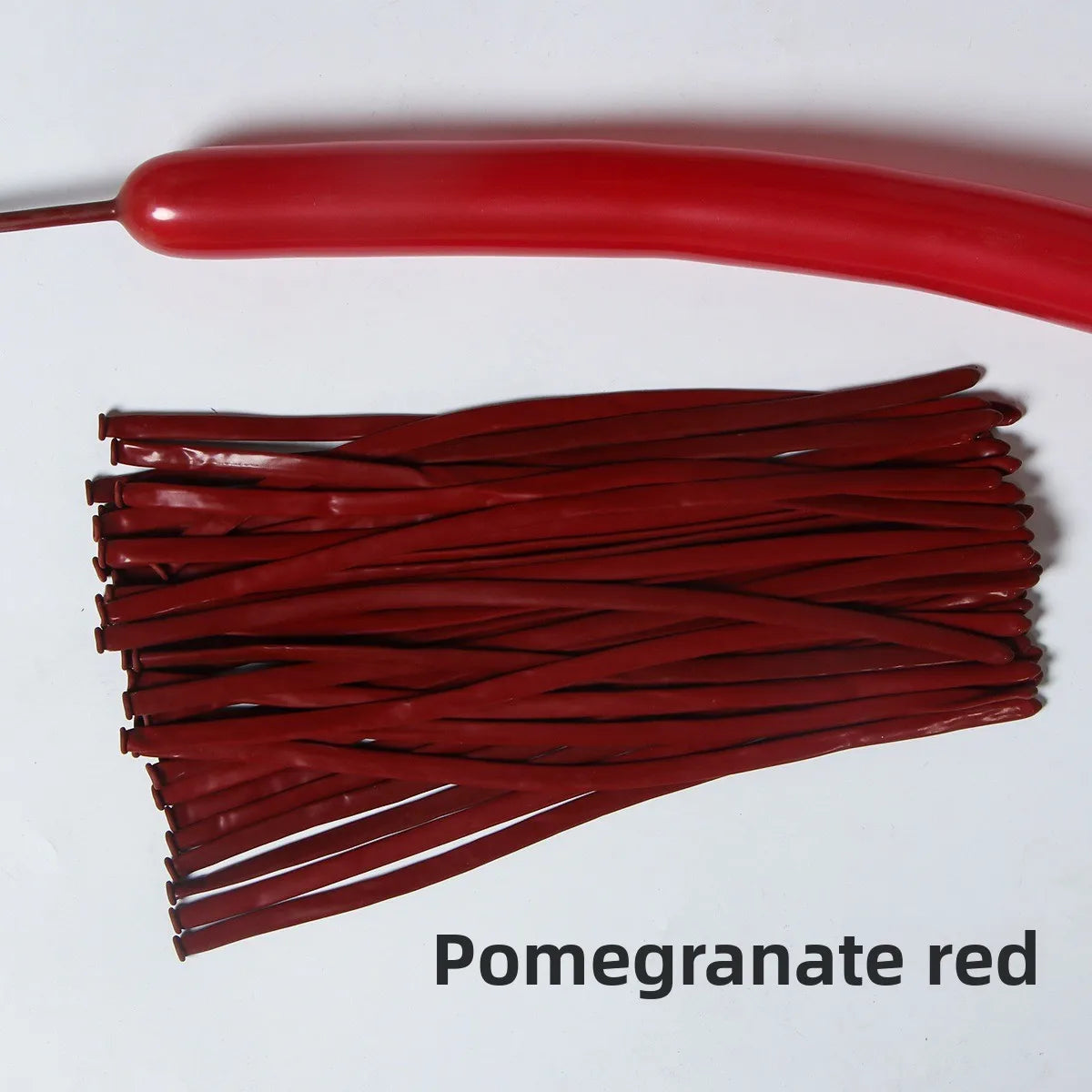 A bundle of pomegranate red latex strip balloons and a single balloon are shown on a white background.