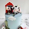 A light blue cake decorated with farm animal toppers including a cow, goat, and lamb.