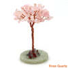 A natural crystal money tree decor featuring pink quartz blossoms on a copper wire stem and a green base.