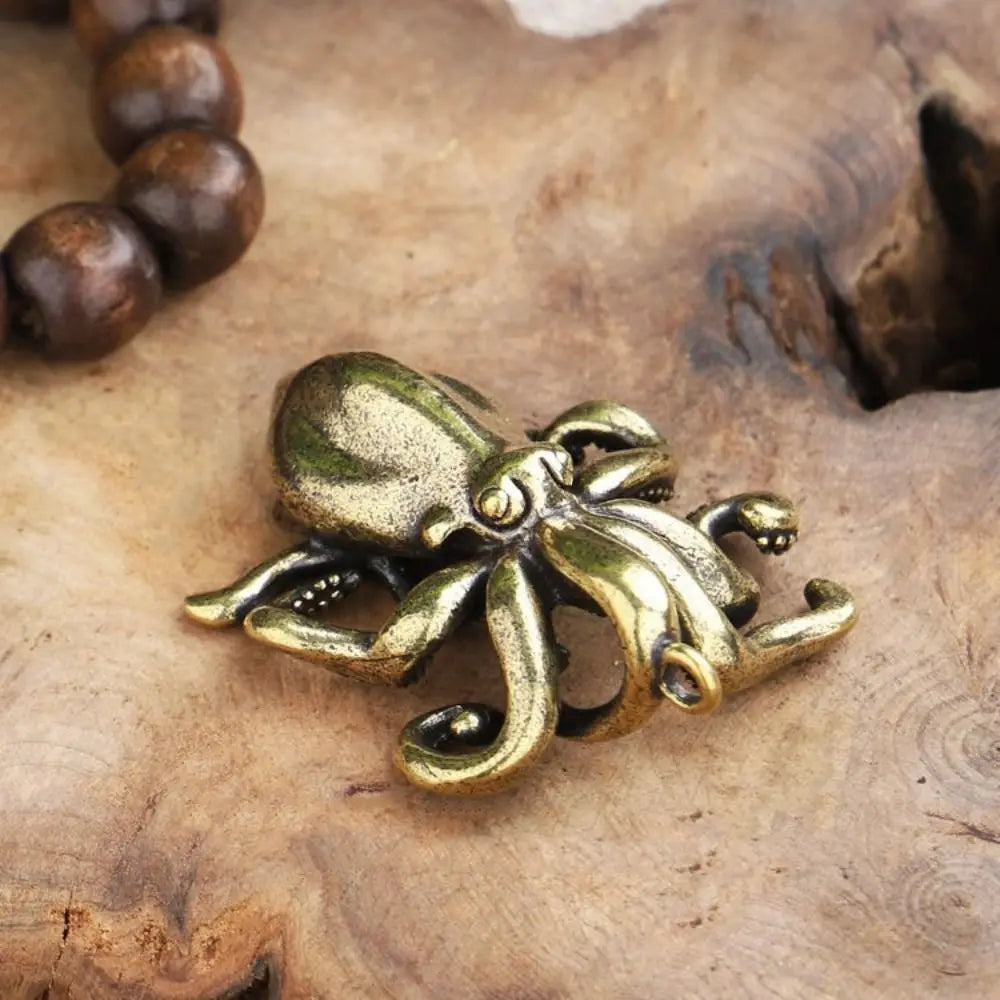 Antique brass octopus desk ornament resting on a wooden surface.