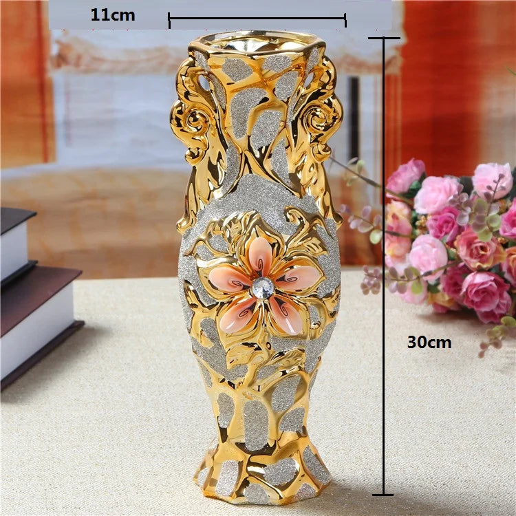 A tall, ornate gold-plated ceramic tabletop vase with floral accents and a textured silver body.