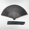A black folding hand fan with a bamboo frame shown in a fan shape and as a flat rectangular object.