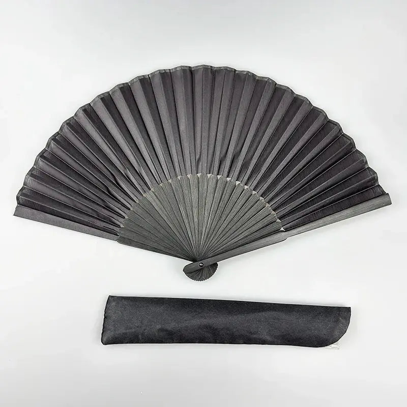 A black folding hand fan with a bamboo frame shown in a fan shape and as a flat rectangular object.