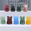 Une rangée d'ornements de chats en cristal sculptés à la main, dans diverses couleurs comme le rose, le gris, le vert et l'or