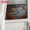 A vintage, rusted metal sign with the inscription Asylum for the Criminally Insane Family Entrance mounted on a white door.