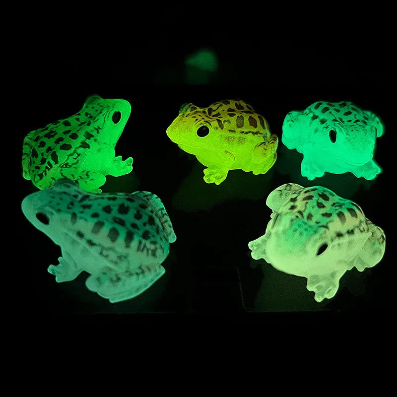 Four glow-in-the-dark resin frog ornaments displayed against a dark background.