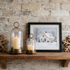 Two antique brass metal candle holders with glass domes sit on a wooden shelf against a stone wall.