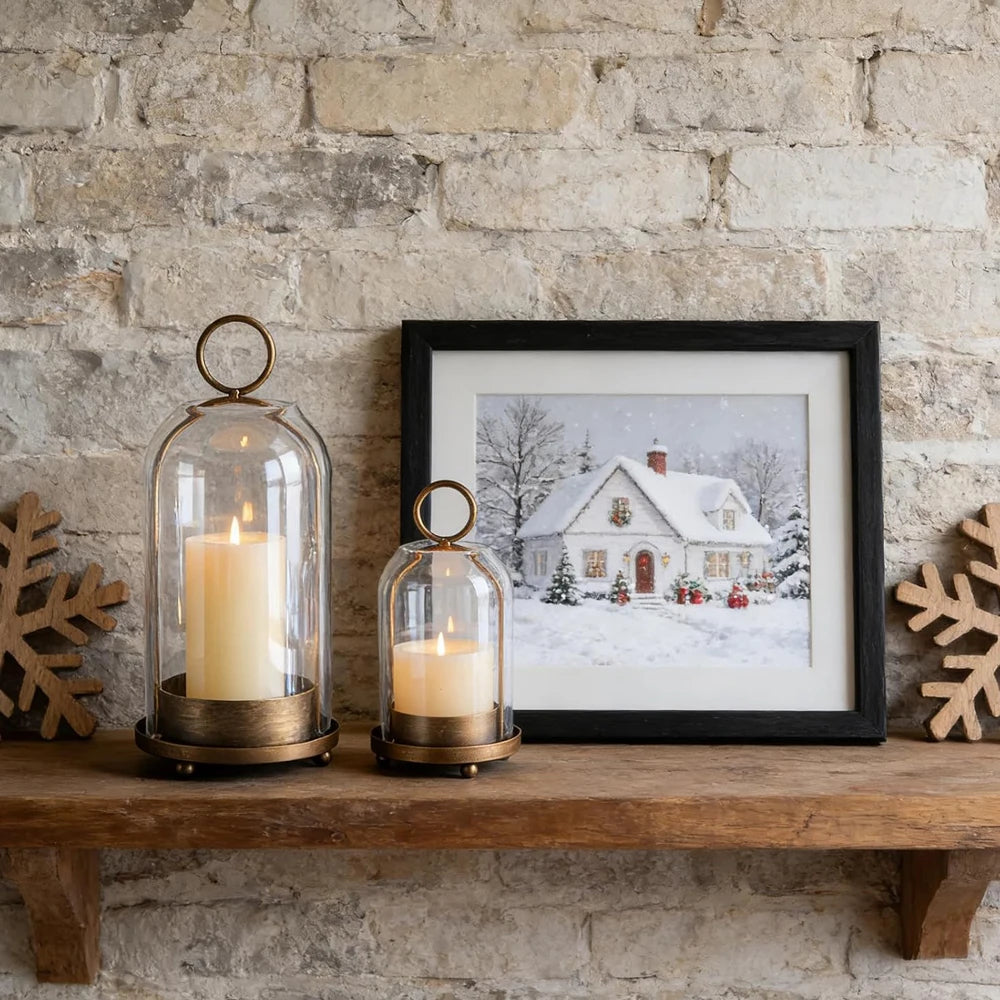 Two antique brass metal candle holders with glass domes sit on a wooden shelf against a stone wall.