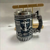 Taza de café con temática militar plateada grabada con detalles azul marino y agarre texturizado, exhibida en una rejilla de 