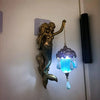 A bronze resin sculpture of a mermaid with a tail, mounted as a wall lamp.