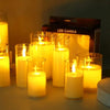 A collection of glowing yellow LED candles in glass holders on a surface.