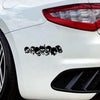 A close-up of a white car's rear section featuring a black decal of multiple skulls and skeletons on the body panel.