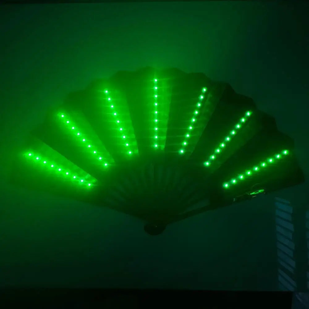 An illuminated folding hand fan with LED lights, showing green light radiating from the center.