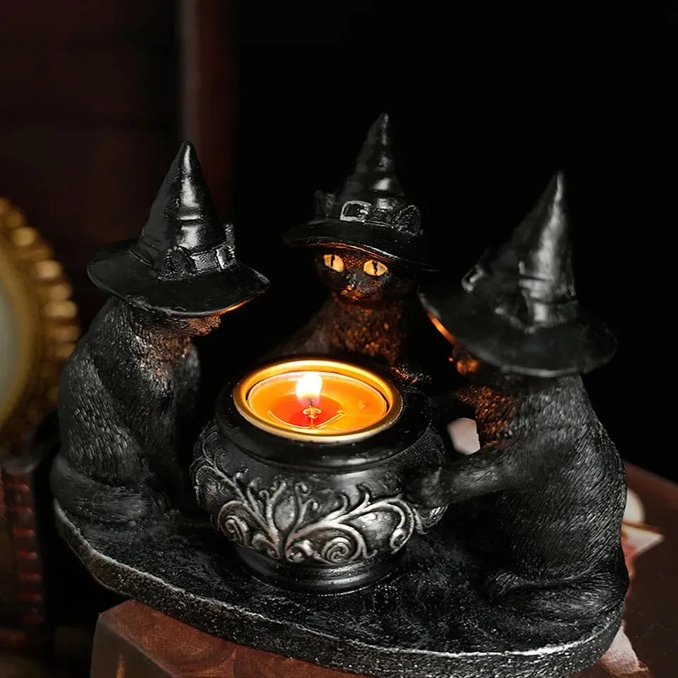A black cat figurine holding a glowing candle in a decorative holder.