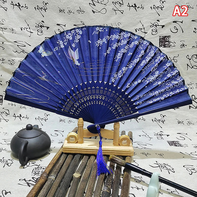 A blue and white elegant vintage Chinese folding hand fan displayed on a wooden stand.