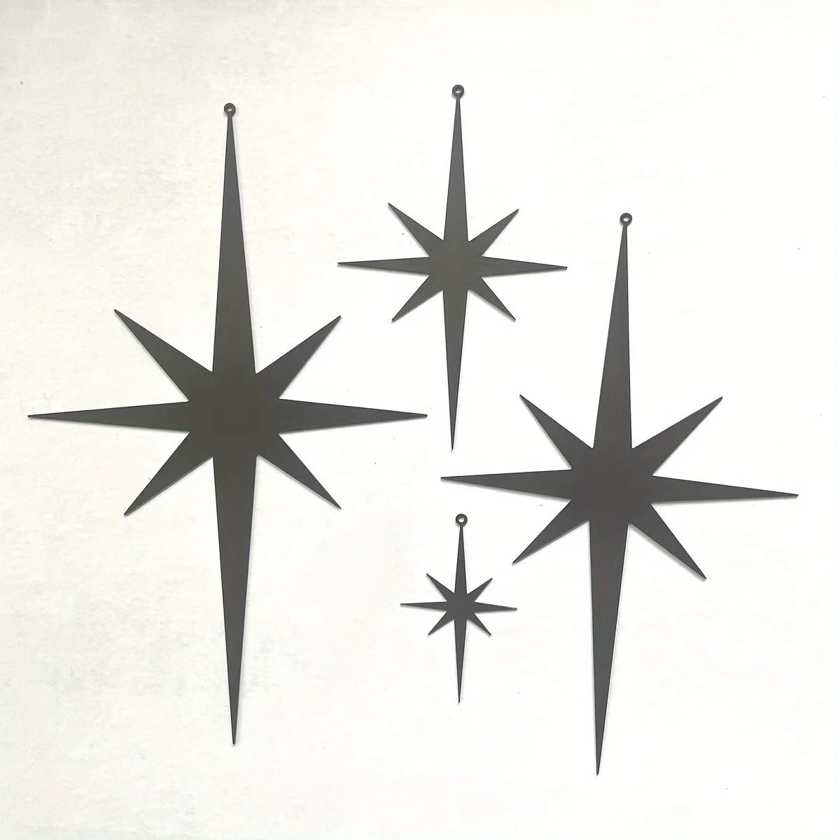 A set of four black metal star wall art pieces with varying sizes and points.