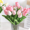 A bouquet of pink and white artificial tulip flowers in a glass vase.