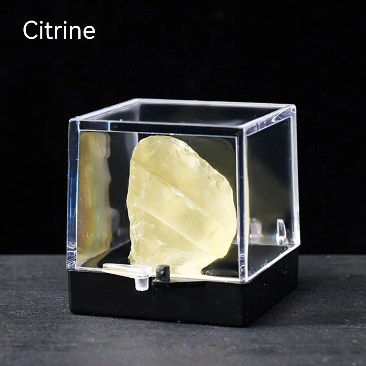 A clear acrylic box displaying a rough, yellowish-green Citrine crystal specimen.