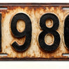 A vintage, rusted aluminum license plate with the year 1980 embossed on it.