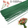 A bundle of flexible green floral wire stems, ranging from 5 to 100 pieces, laid out diagonally with a finished floral arrang