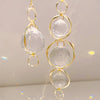 Une paire de pendentifs en cristal doré avec des pierres claires sphériques, suspendus par des boucles.