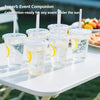 A set of reusable clear plastic drinking cups with flat straws and lemon slices, ready for an outdoor event.