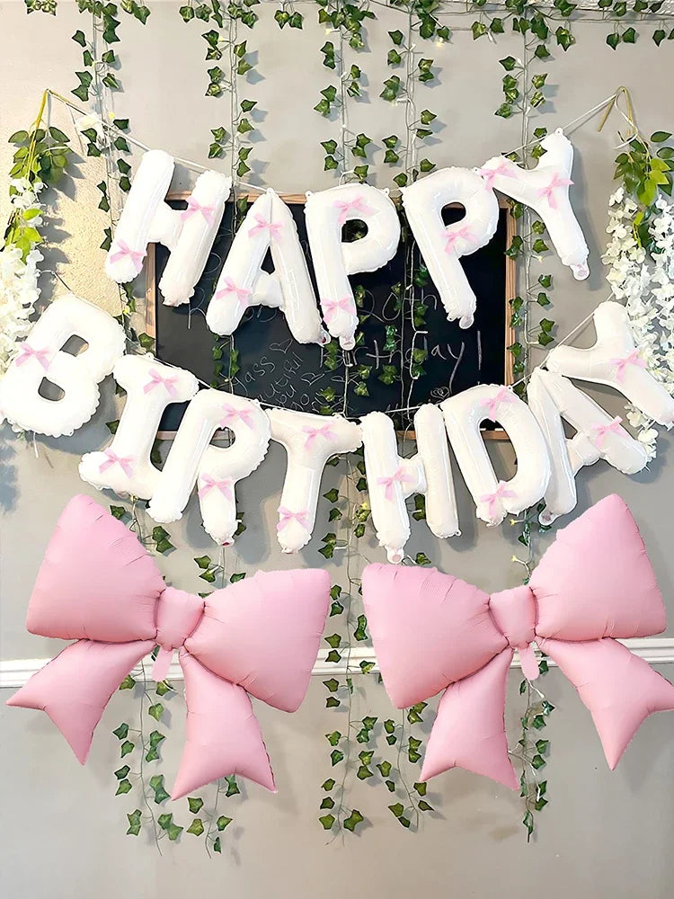 A decorative banner featuring white and pink letters spelling 'Happy Birthday' made from balloons and accented with pink bows
