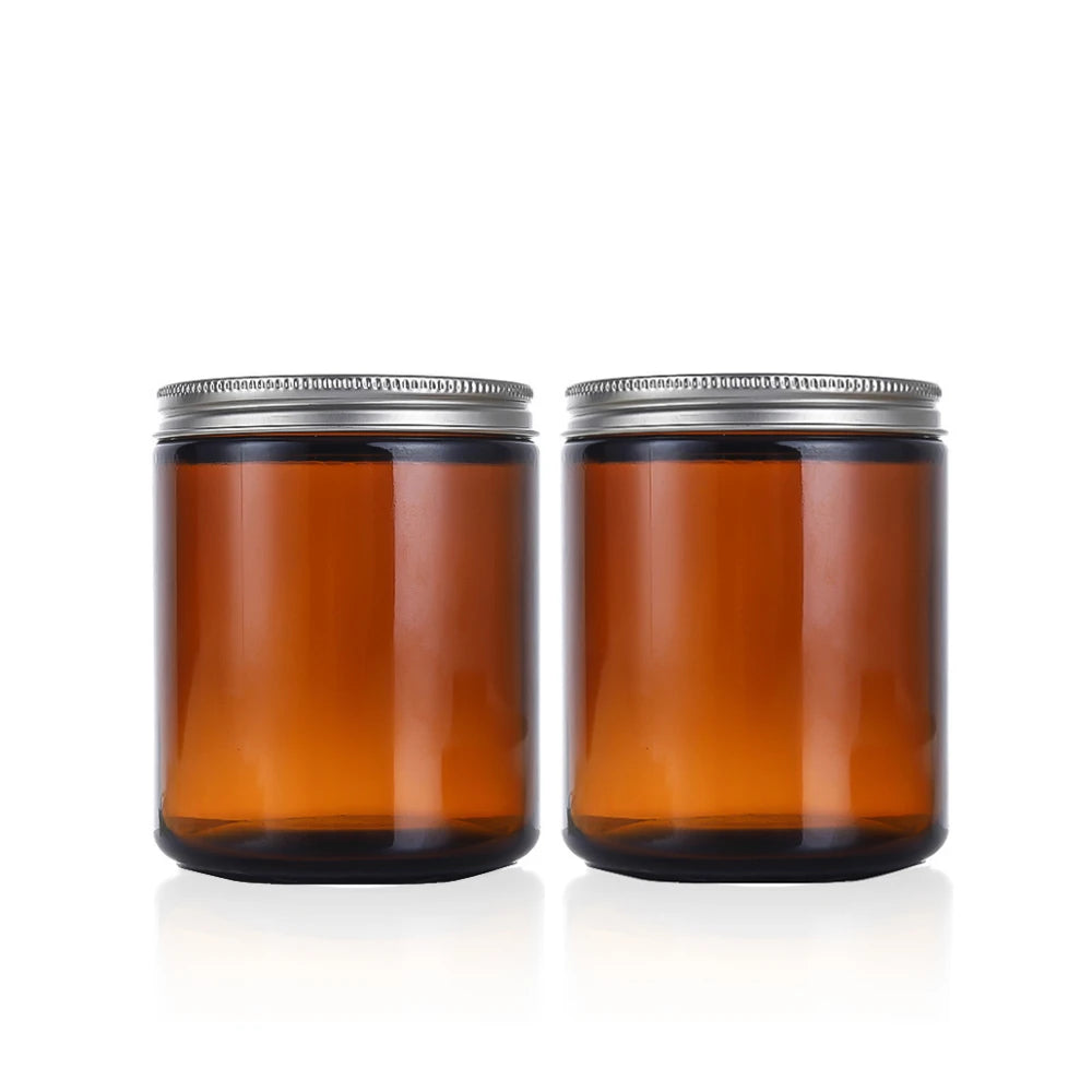 A set of two amber glass jars with metal lids and labels sitting on a white surface.