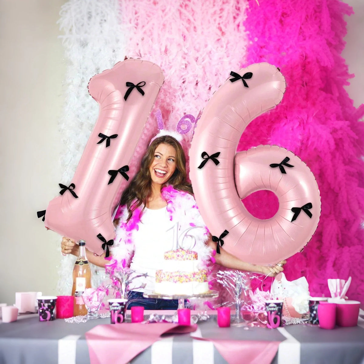 Pink foil number balloons 1 and 6 with black bows displayed on a table.