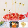 Gold accent bamboo cocktail skewers with diced tomatoes served in a white bowl