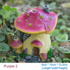 A small resin garden statue of a mushroom house with pink and yellow accents growing in natural foliage.