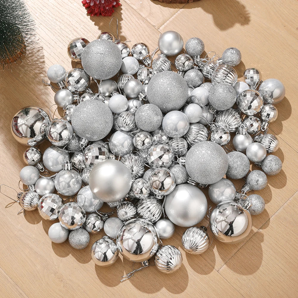 Assorted silver and gold Christmas tree ornaments and baubles scattered on a wooden surface.