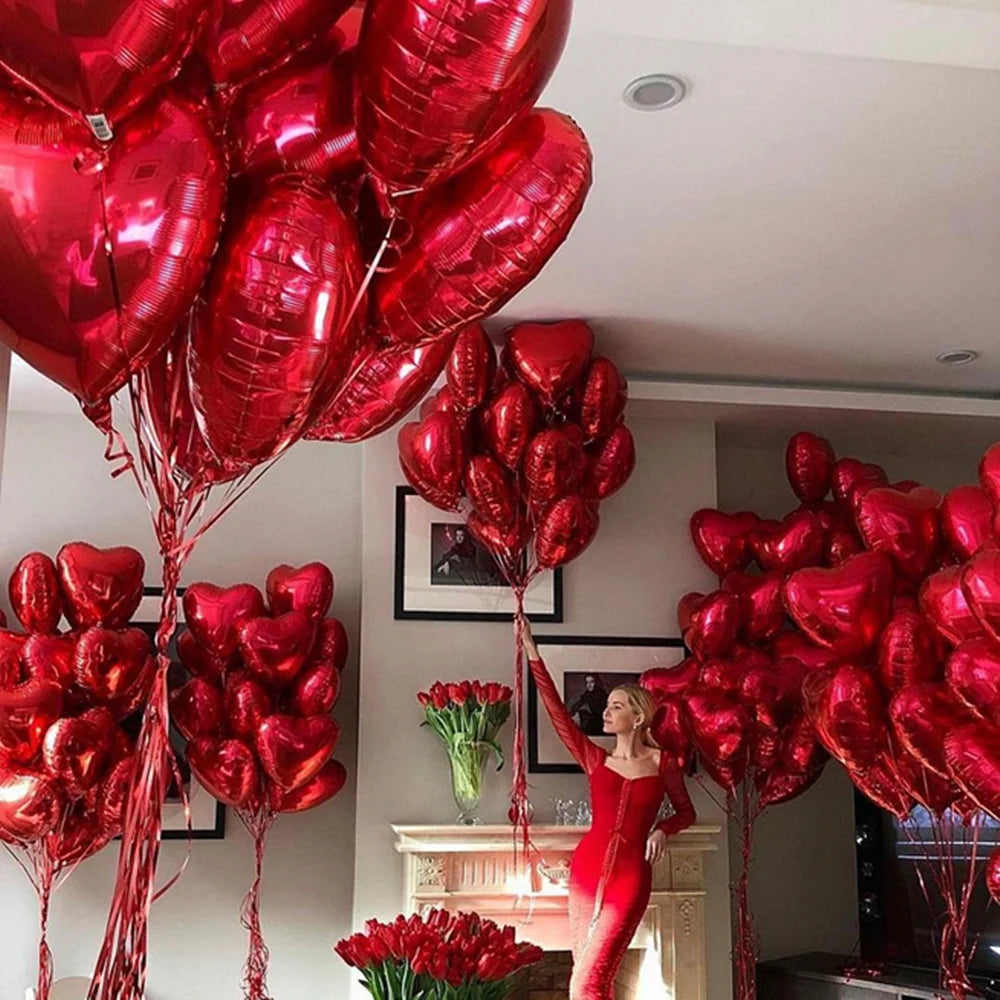 A large arrangement of red heart-shaped foil balloons is displayed indoors.