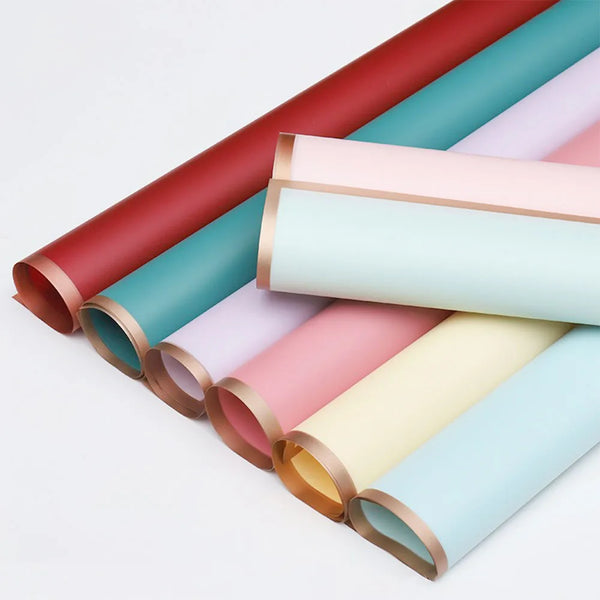 Un juego de diez rollos de papel de regalo floral con borde dorado en varios tonos pastel, incluyendo rosa, verde menta y cre