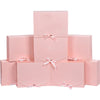 A stack of pink kraft paper gift boxes tied with sheer pink ribbons.