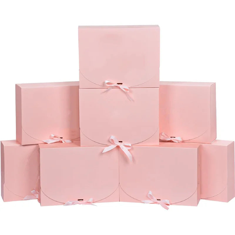 A stack of pink kraft paper gift boxes tied with sheer pink ribbons.