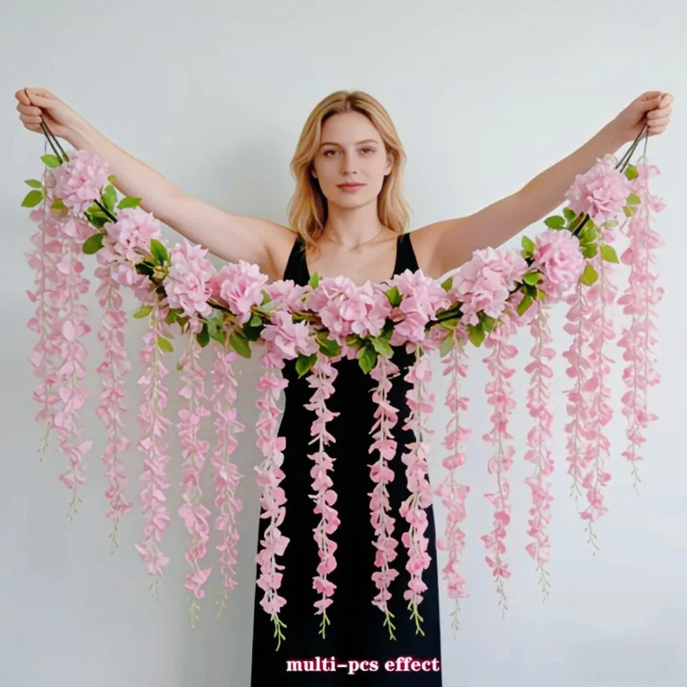 A woman holds out her arms displaying a lush pink silk wisteria hanging vine garland.