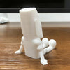 A white 3D printed Moai statue figurine with movable joints standing on a wooden surface.