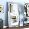 A rectangular silver crystal rhinestone wall mirror with a sparkling frame hanging on a light blue wall.