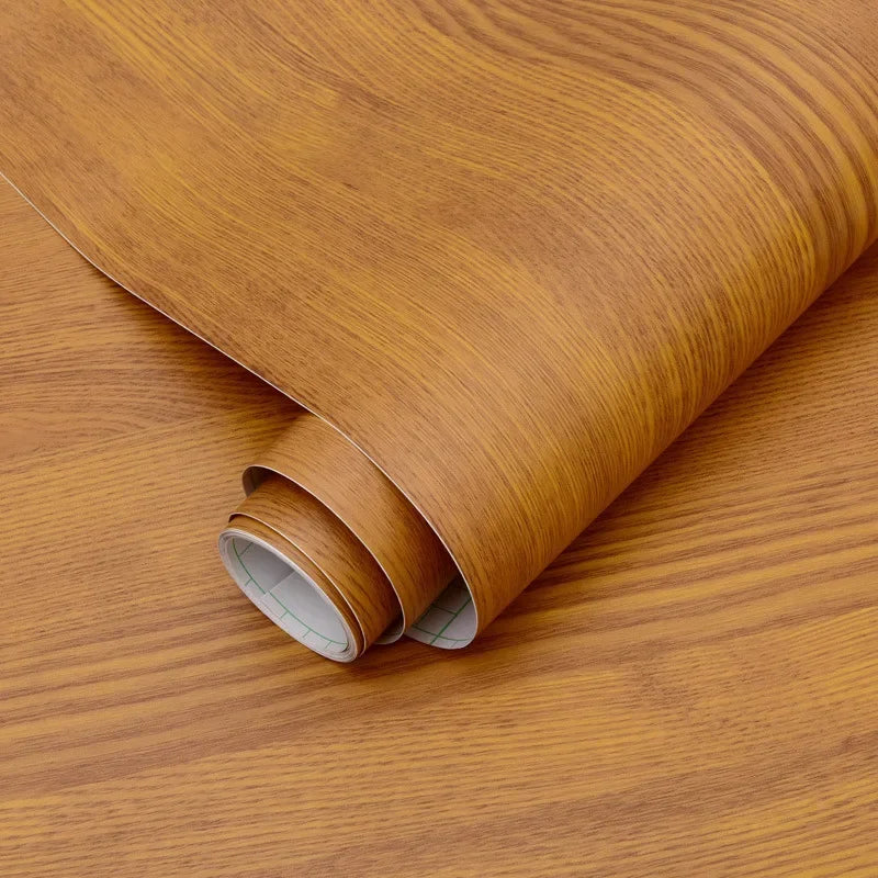 A roll of self-adhesive PVC wallpaper film with a wood grain texture, showing the rolled edge.