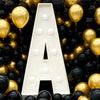 A large white marquee letter shaped like the letter A is displayed amidst a dense background of gold and black balloons.