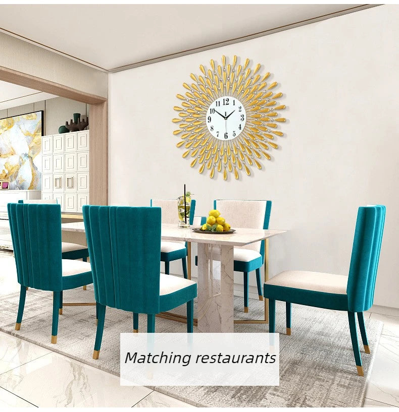 A modern minimalist metal wall clock with a sunburst design hangs on a white wall above a dining table.