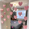 Pink heart-shaped string door curtain with romantic bead design hanging in a room.