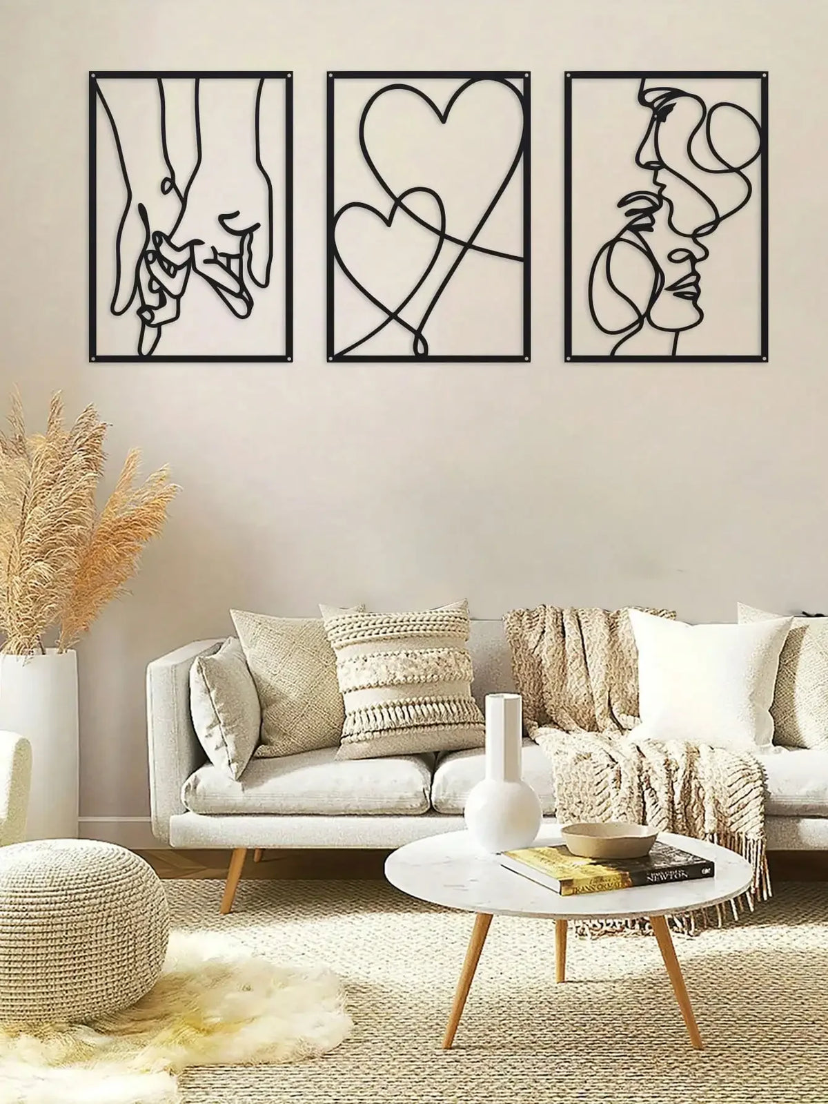 A set of three black line art prints depicting holding hands, a heart, and a profile face, displayed on a light-colored wall.