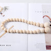 A necklace made of light beige wooden beads is displayed on a white background.